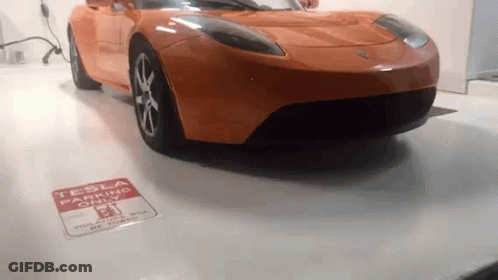 Orange Tesla Parked By Tesla Parking Sign GIF