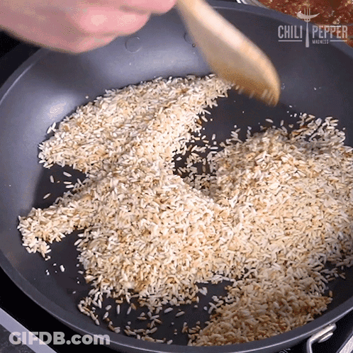Pan Of Rice Stirred With Wooden Spoon From Chili Pepper Markets GIF