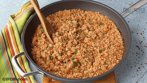 Pan Of Rice With Wooden Spoon And Chili Peppers GIF