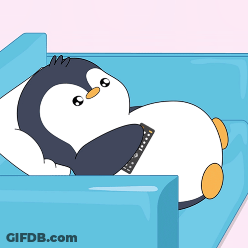 Penguin Laying On Blue Couch With Remote Control GIF