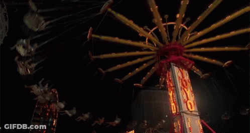 People Are Riding A Merry Go Round At A Carnival At Night .. GIF
