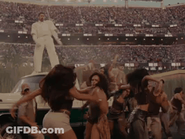 People Dancing In Stadium With Man In White Suit On Car GIF