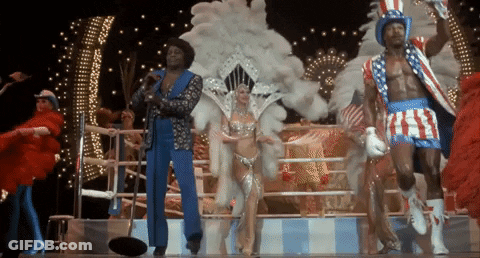 People Dancing On Stage, One With American Flag Hat GIF