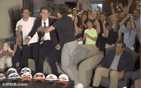 People Gathered Around Table Of Hats GIF
