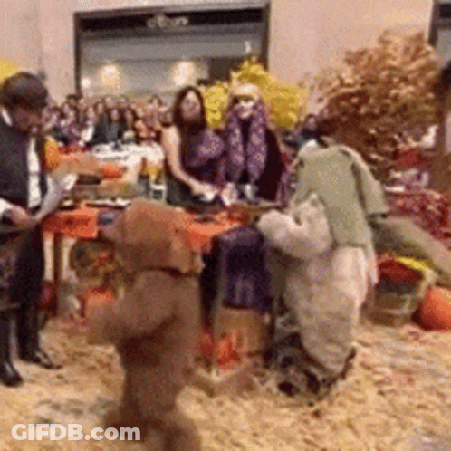 People Gathered Around Table With Stuffed Animals GIF