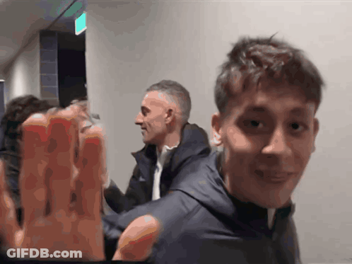 People In Hallway With Green Exit Sign GIF