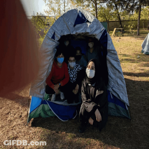 People In Masks Sitting In Tent GIF