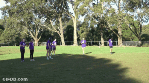 People In Purple Shirts Standing On Grass GIF