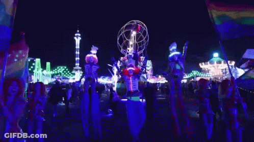 People On Stilts In Front Of Carnival Ride GIF