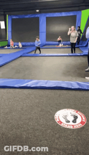 People Playing On Trampoline With Stand Here Sign GIF