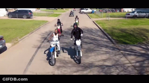 People Riding Dirt Bikes Down Street GIF