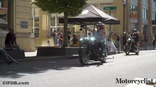 People Riding Motorcycles On Street With Motorcyclist Text GIF