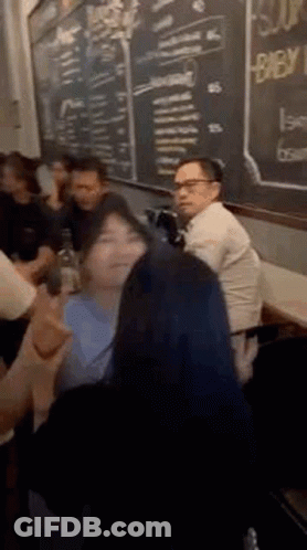 People Sitting At Table In Front Of Chalkboard GIF