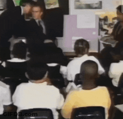People Sitting In Classroom With Man In Suit GIF