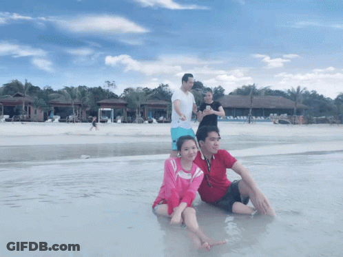People Sitting On Beach With Woman Taking Photo GIF