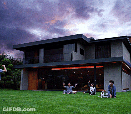 People Sitting On Grass By Large House GIF