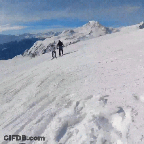 People Skiing Down Snowy Mountain GIF