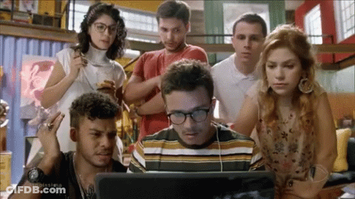 People Standing Around Man Looking At Laptop GIF