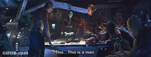 People Standing Around Man On Table Saying This Is A Man GIF