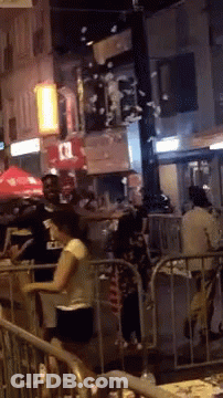 People Standing By Fence On Crowded Street GIF