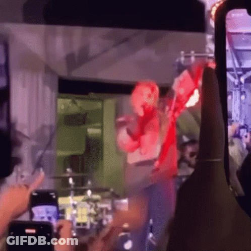 People Taking Pictures Of Man In Red Costume On Stage GIF