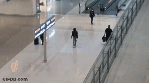 People Walking In An Airport With A Sign That Says ' Arrivals ' GIF