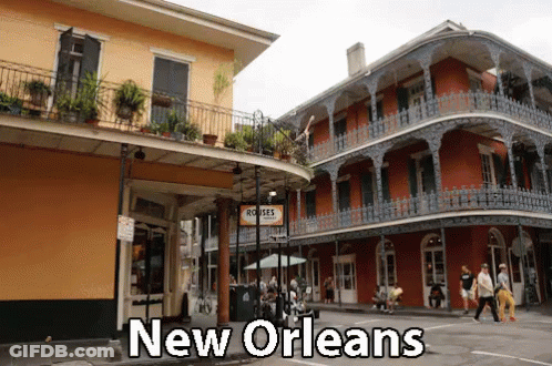 People Walking In Front Of Building Saying New Orleans GIF