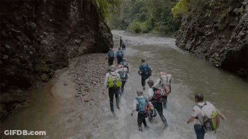 People Walking Through River With Backpacks GIF