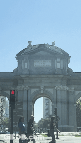 People Walking Under Stone Archway Puerta De Arco De Madrid GIF