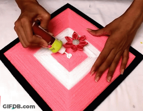 Person Applying Glue To Pink Square With Red Flower GIF