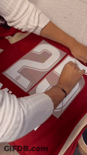 Person Applying Stickers To Red Shirt With 20 GIF