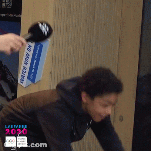 Person Being Interviewed In Front Of Watch Now Sign GIF