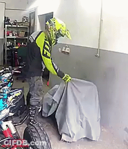 Person Covering Motorcycle In Garage GIF