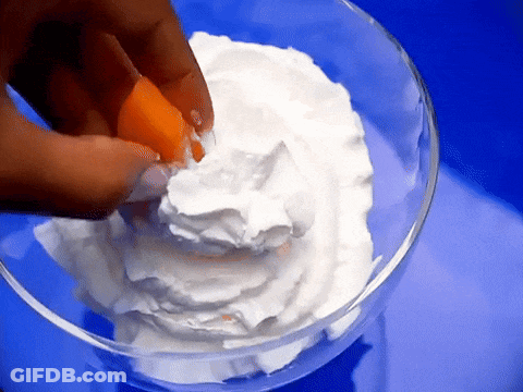 Person Cracking Egg Into Whipped Cream Bowl GIF