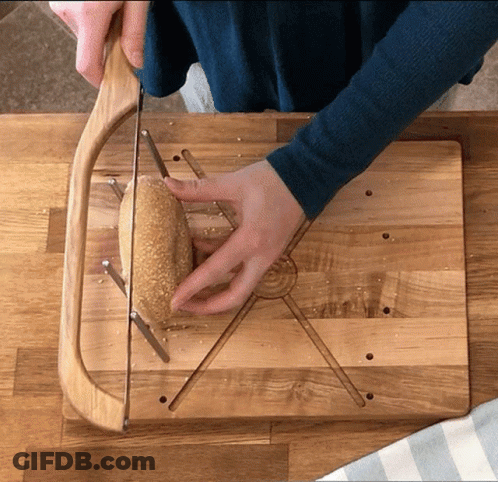 Person Cutting Bread On Wooden Board GIF