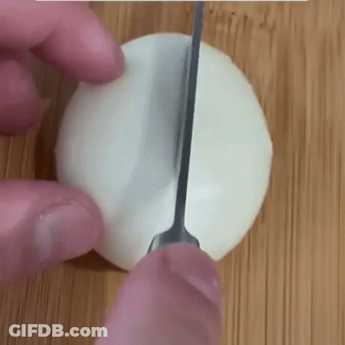 Person Cutting Egg On Cutting Board With Knife GIF
