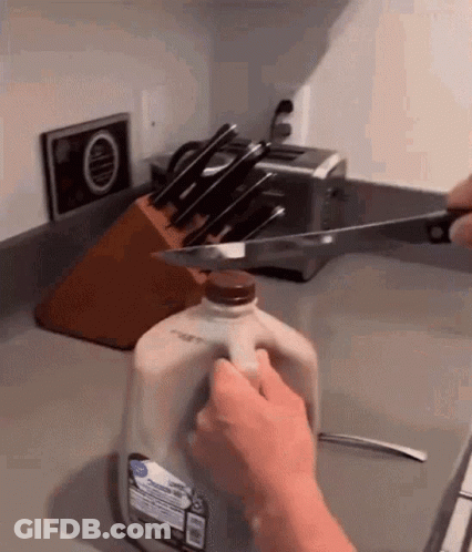 Person Cutting Gallon Of Milk With Knife GIF