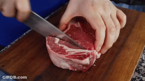 Person Cutting Meat With Knife On Wooden Cutting Board GIF