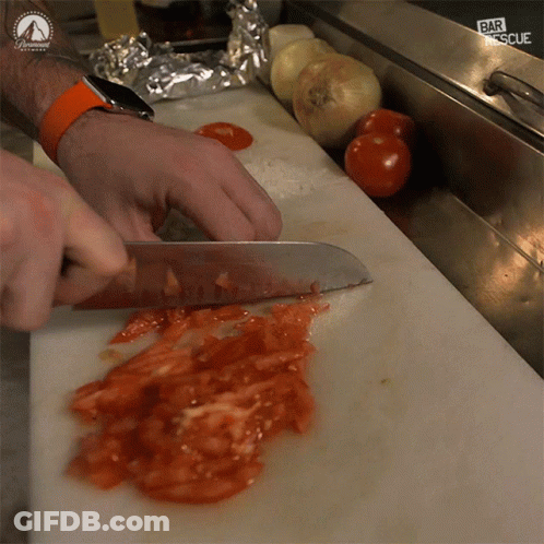 Person Cutting Tomatoes On Cutting Board With Paramount Logo GIF