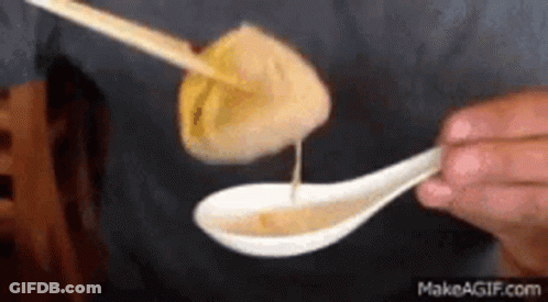 Person Dipping Dumpling Into Spoon Of Sauce GIF