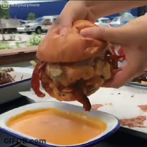 Person Dipping Hamburger Into Cheese Sauce GIF