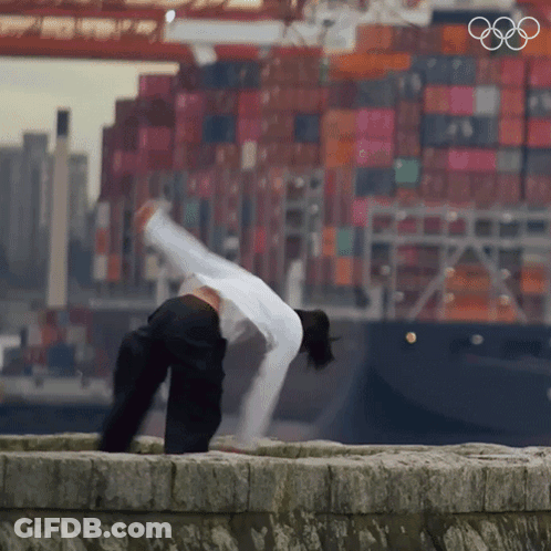 Person Doing Handstand In Front Of Large Ship GIF