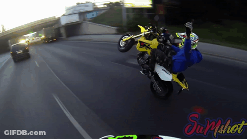 Person Doing Motorcycle Trick In Front Of Sum Shot Sign GIF