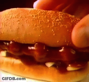 Person Eating Hamburger With Ketchup And Onions GIF