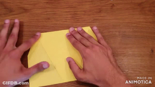 Person Folding Yellow Paper On Wooden Table GIF