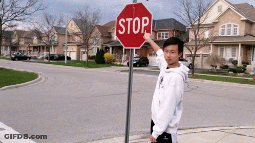Person Hanging Upside Down Next To Red Stop Sign GIF