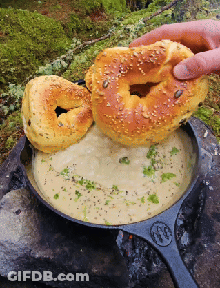 Person Holding Bagel Over Soup GIF