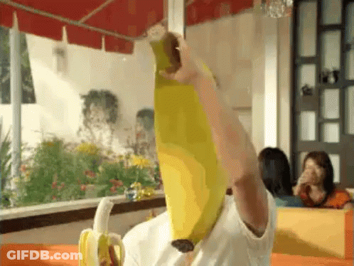 Person Holding Banana Over Head In Restaurant GIF