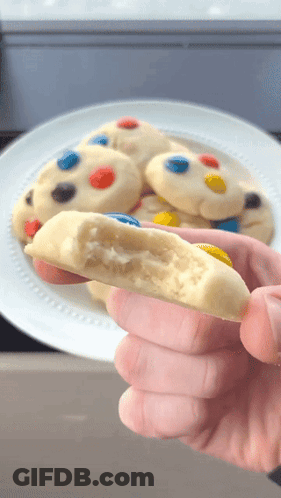 Person Holding Bitten Cookie And Plate Of Cookies GIF
