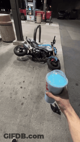 Person Holding Blue Drink In Front Of Motorcycle GIF
